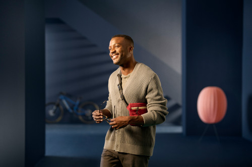 A man smiles while walking and holding his glasses